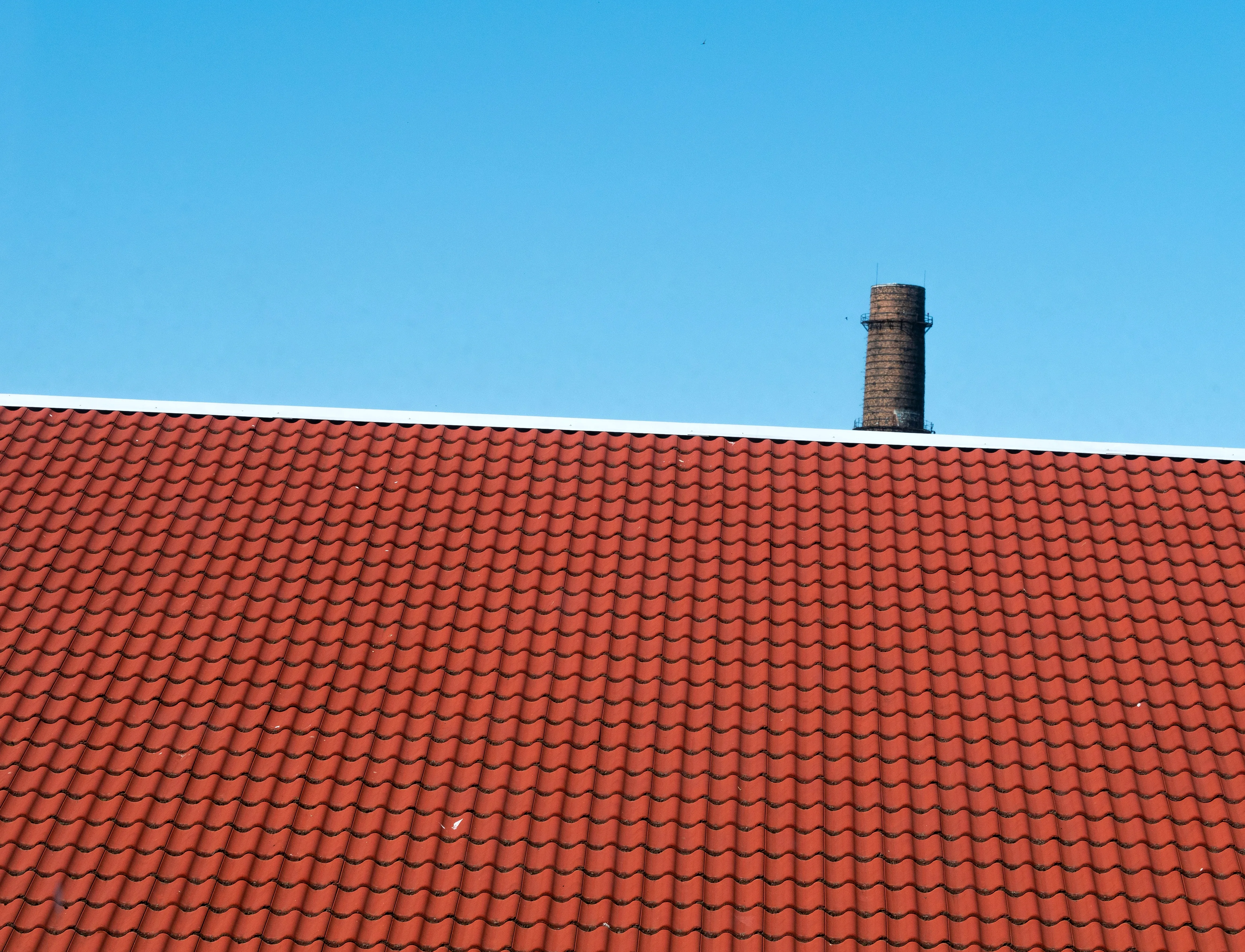 Impermeabilización en Berango: pide presupuesto. Tejado de teja roja con una chimenea y cielo despejado